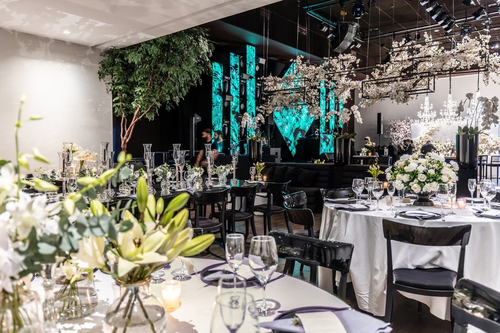 An elegant banquet hall dressed for a wedding reception, floral centrepieces and warm lighting in place before guests arrive