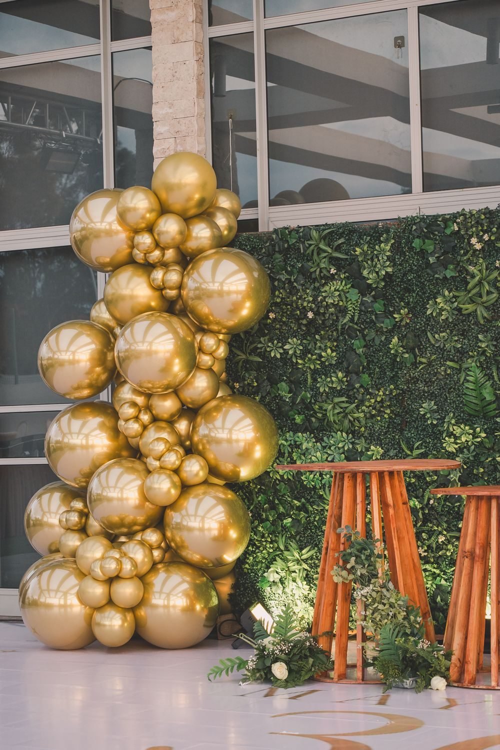 A gold balloon arrangement set against greenery for a birthday celebration