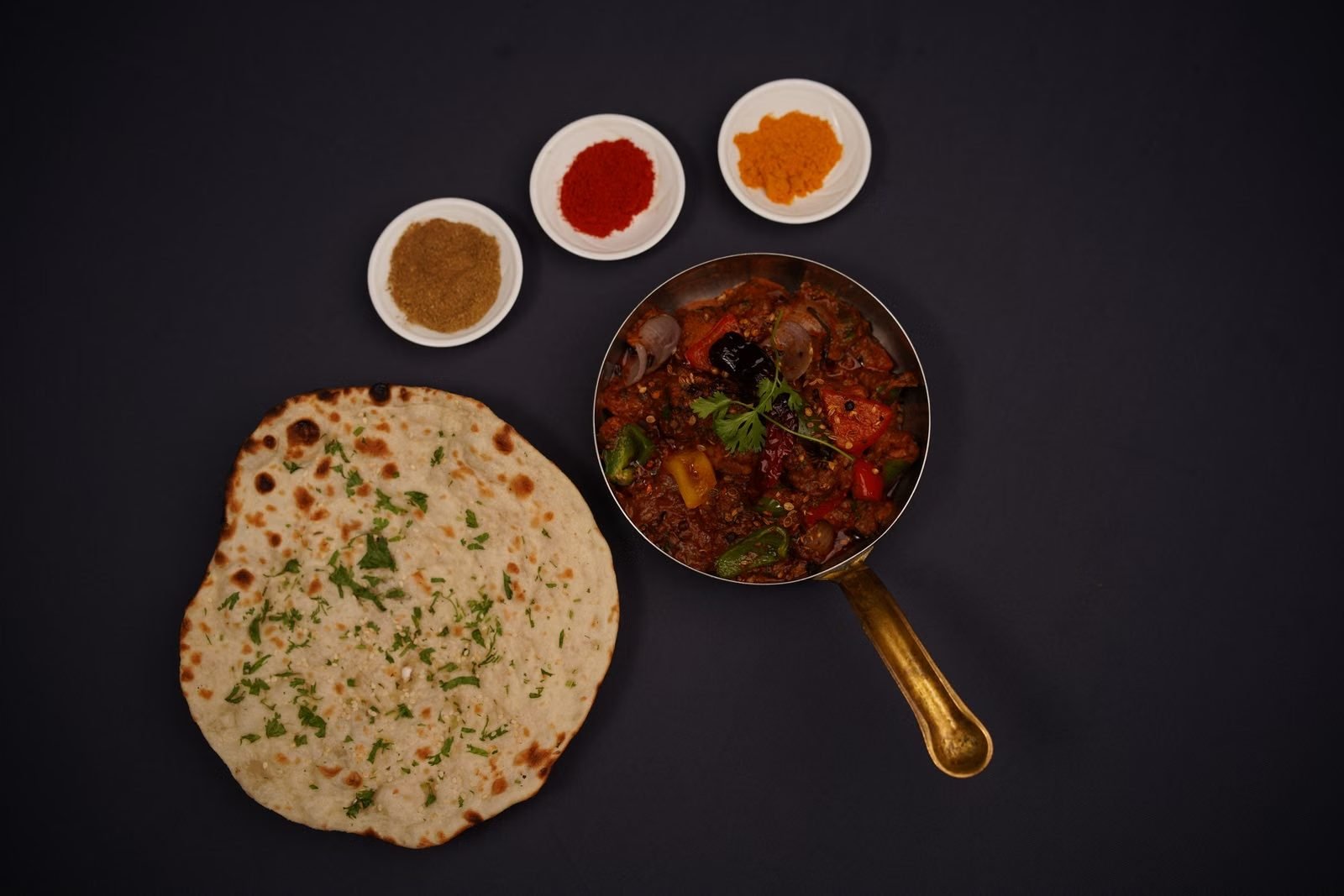 Freshly baked flatbread and a curry pan photographed from above