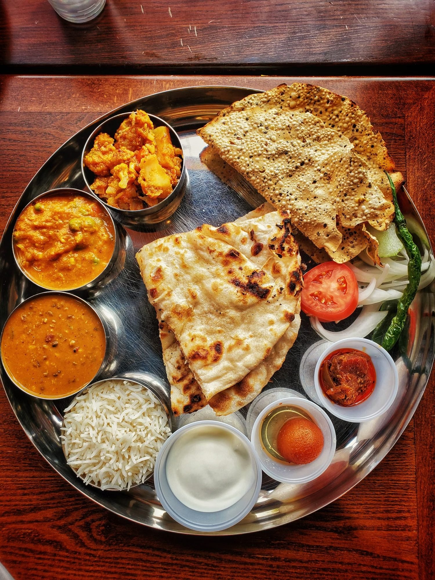 A thali tray of curries, freshly baked naan and assorted chutneys
