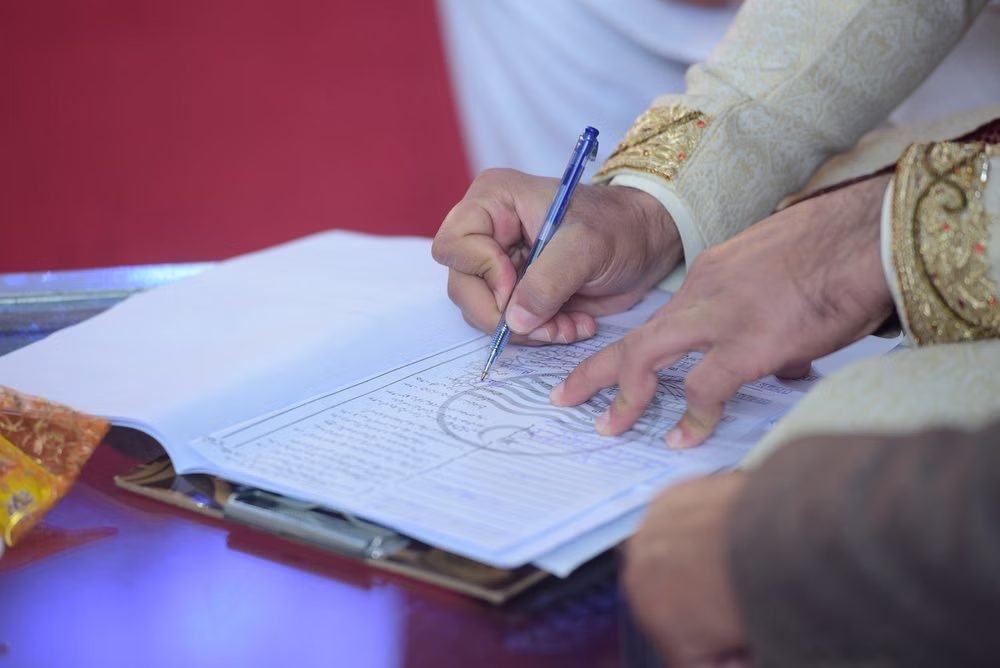 A groom signing the nikah nama during a Pakistani wedding ceremony